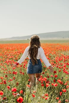 Woman poppies field. Back view of a happy woman with long hair in a poppy field and enjoying the beauty of nature in a warm summer day