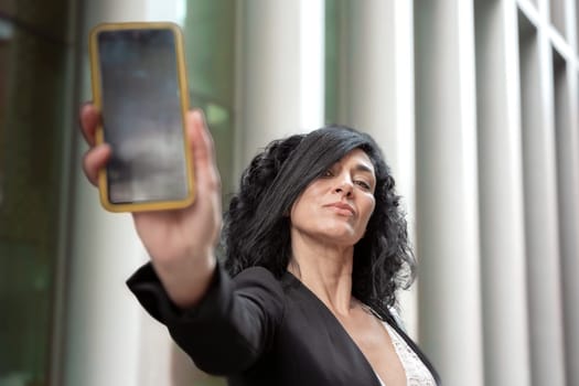 woman shows a smartphone with an empty screen for advertising or presentation, look at camera., smiling. Gadget Concept