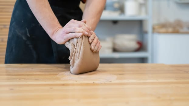 A potter kneads clay before using it in the workshop. Close-up of a man's hands