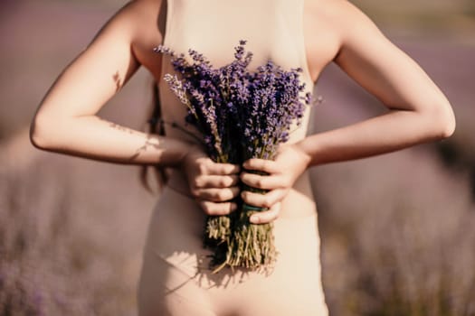 girl holding bouquet lavender flowers. The flowers are purple and the woman is wearing a tan top. Concept of calm and relaxation, as lavender is often associated with these feelings