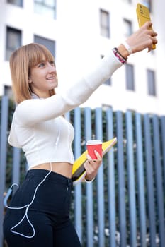 Young caucasian woman having a video call with cell phone and smiling outdoors.
