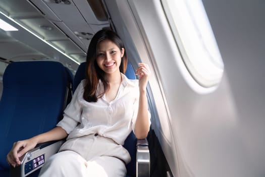 Businesswoman smiling while sitting in airplane seat. Concept of business travel and professional journey.