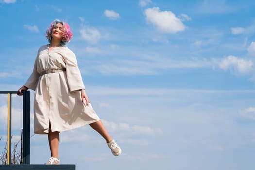 A woman with colored hair walks outdoors. Portrait of a girl against the blue sky