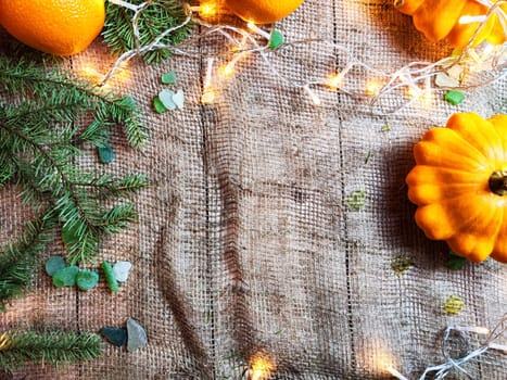 Festive decoration with a bouquet and branches of spruce, bright glowing garlands, burlap, oranges. Background for Christmas and New Year. Abstract texture, frame, place for text, copy space