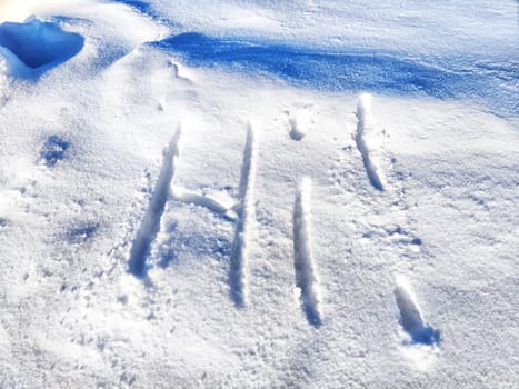 Inscription Hi, written on white background of the snow. Top view. Flat lay. New year and Christmas. Greeting morning, day, weather, sun and people