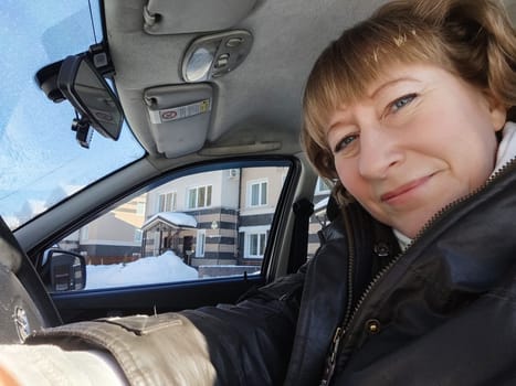 Middle aged woman in a car taking a selfie while enjoying a drive. Female mature driver posing inside car. Funny happy tourist girl in alone travel