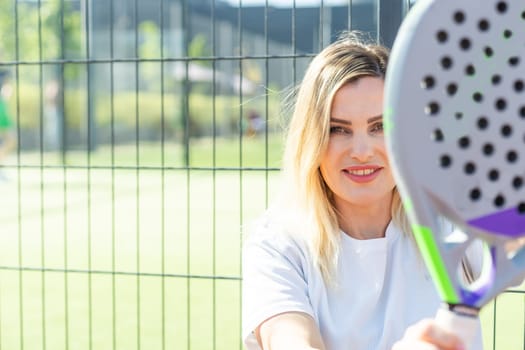 Happy female paddle tennis player during practice on outdoor court looking at camera. Copy space. High quality photo