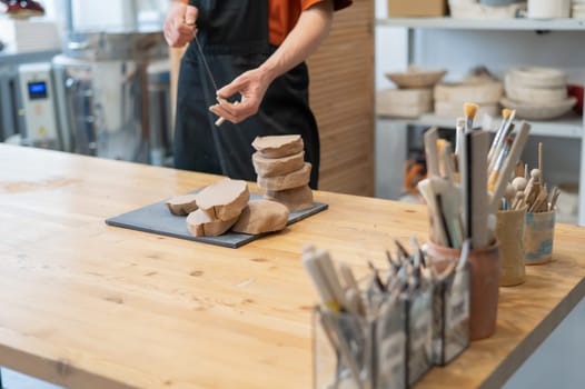 A potter cuts a piece of clay into pieces before using it in the workshop