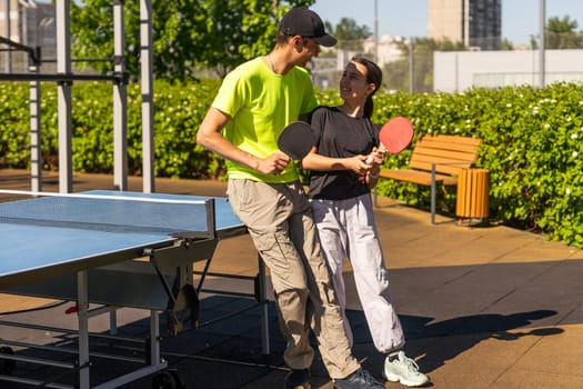 Happy man with his daughter playing ping pong in park. High quality photo