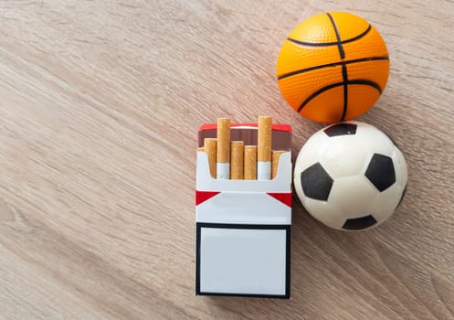 Smoking or sports. Sport ball and pack of cigarettes on table background. Top view. High quality photo