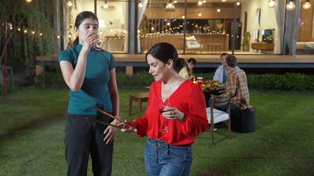 Family gather celebrate holiday. Focus Mother and grandmother drink wine and grill food for family member in dinner party. Outdoor activity spend time with relative cross generation gap. Divergence.