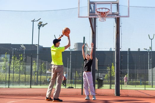 father and daughter playing basketball together on playground. High quality photo