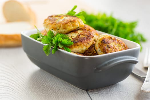 fried meat cutlets in a ceramic form on a wooden table .