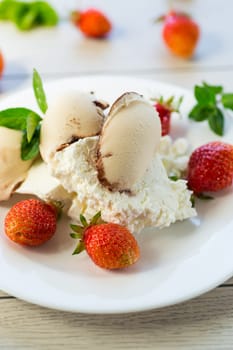 fresh organic cottage cheese with strawberries and ice cream in a plate on a wooden table .