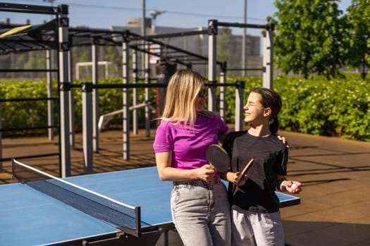 Adult woman instructor teaching girl play table tennis. High quality photo