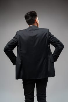 Young businessman from the back standing on gray background in studio