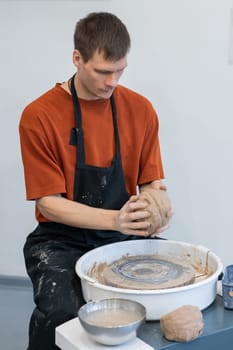 A potter kneads clay before using it on the potter's wheel. Vertical photo