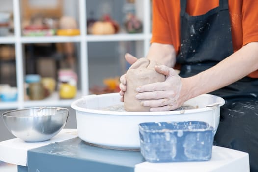 The potter kneads the clay before using it on the potter's wheel. Close-up of a man's hands