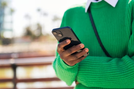 unrecognizable black woman using mobile phone outdoors, concept of technology of communication and modern lifestyle, copy space for text