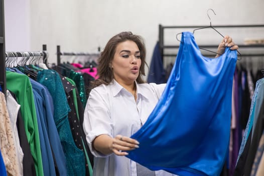 A fat woman chooses clothes in a plus size store