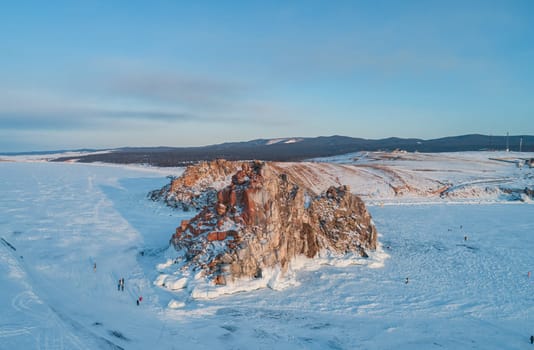Aerial shot of Shamanka rock and Cape Burkhan on Olkhon. Beautiful view on frozen Baikal. Panoramic winter landscape. Popular touristic destination