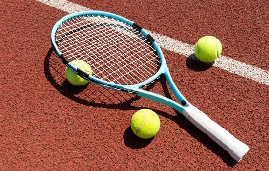 Racket with a tennis ball on a red clay court. High quality photo