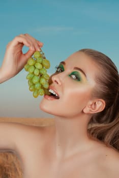 Beautiful young woman with grape bunches on summer green and yellow background