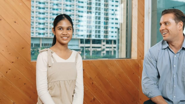 Young student smiling while listening other student in meeting or group discussion. Cute teenager talking about her experience and sharing to friends in mixed races. Creative education. Edification.