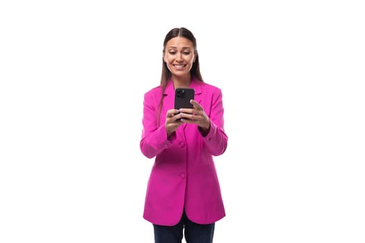 young smart european brunette with black hair dressed in a stylish raspberry jacket is chatting on a smartphone.