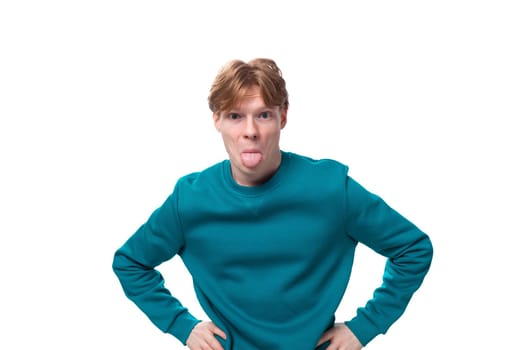 young handsome red-haired man with a blue sweater looks attentively at the camera.