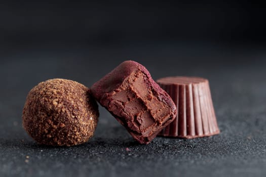 Premium gourmet chocolate handmade truffles from confectionery, homemade dark chocolate candies on black background