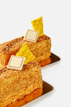 Delicious honey pastries coated with fine biscuit crumbs topped with yellow chocolate honeycomb pieces, served on golden cardboards on white background
