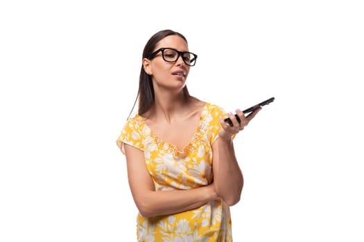young pretty Caucasian woman in a yellow summer T-shirt thinks where to call on a smartphone.