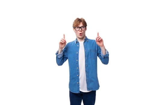 young smart red-haired guy dressed in a blue shirt wears glasses on a white background with copy space.