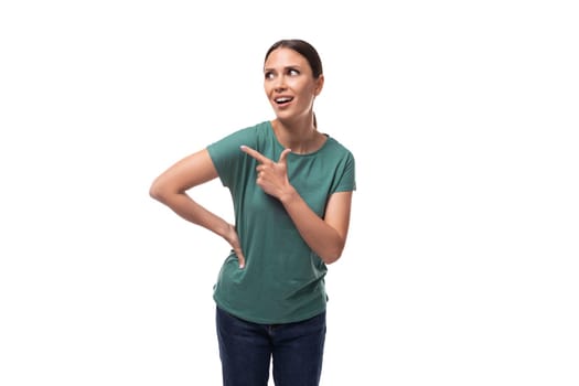 30 year old positive european brunette woman with a ponytail hairstyle is dressed in a green t-shirt and jeans holding her index finger up.