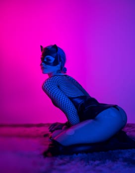 sexy girl in costume and mask bdsm games in neon light with empty background