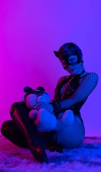 sexy girl in costume and mask bdsm games in neon light with empty background