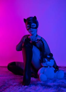 sexy girl in costume and mask bdsm games in neon light with empty background
