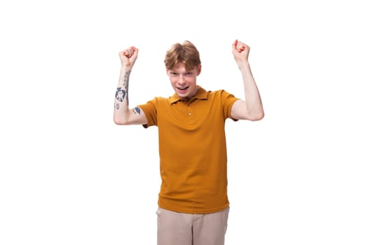 a young handsome red-haired man with a haircut and a tattoo on his arm is dressed in a summer yellow t-shirt.