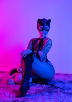 sexy girl in costume and mask bdsm games in neon light with empty background