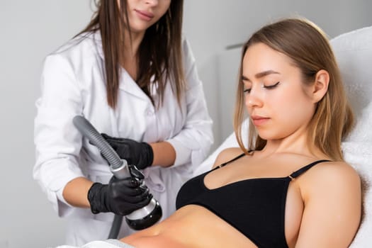 Lady adjusts hair during vacuum cavitation procedure. Client happy to notice improvements in skin texture and elasticity in treated belly area