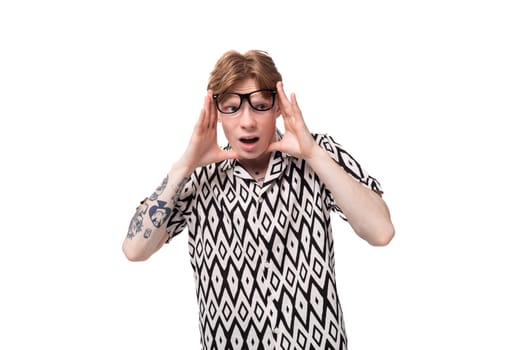 portrait of a young red-haired guy in glasses dressed in a summer shirt.