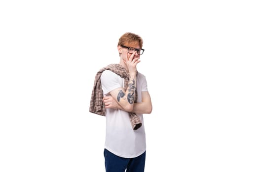 young european man with golden red hair wears glasses and a shirt over a t-shirt.