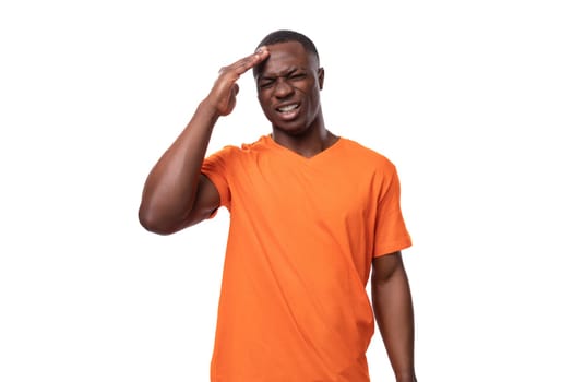 young american man dressed in orange corporate t-shirt trying to remember and brainstorming.