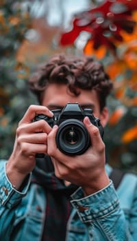 A creative photographer with curly hair is framing a shot of the vibrant, colorful foliage through the viewfinder of a professional dslr camera, immersed in the natural surroundings