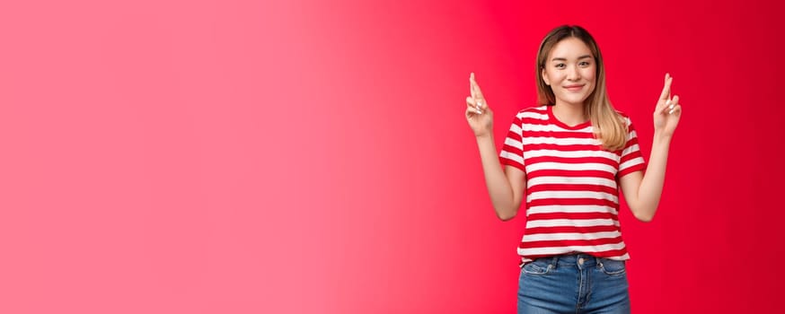 Fingers crossed for you, good luck. Cheerful cute asian blond girl wear striped t-shirt praying everything ok, wanna wish fulfill, smiling broadly look camera hopeful, anticipate positive results.