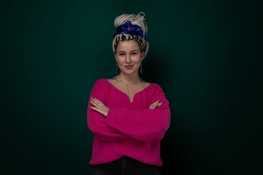 A woman wearing a pink sweater is striking a pose for a picture. She looks directly at the camera with a slight smile. The background is blurred, emphasizing the main subject.