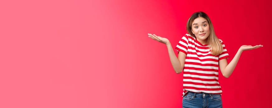 Portrait unbothered relaxed chill blond girl shrugging hands spread sideways clueless, woman smiling indifferent have no idea, stand confused hesitant, stand red background questioned.