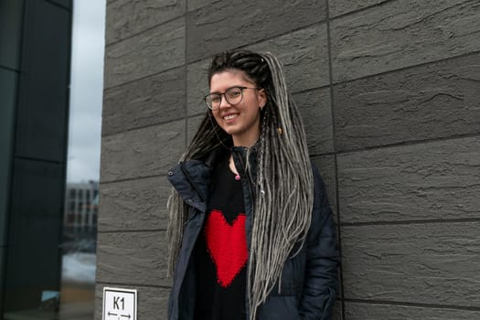 Urban charming woman with dreadlocks hairstyle looks informal and unusual.