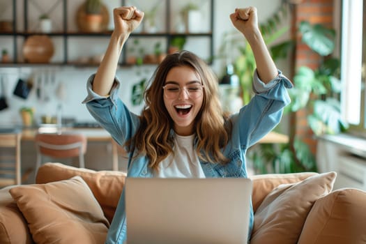 Happy overjoyed laughing woman celebrating success raising her hands up while working on laptop sitting at home office